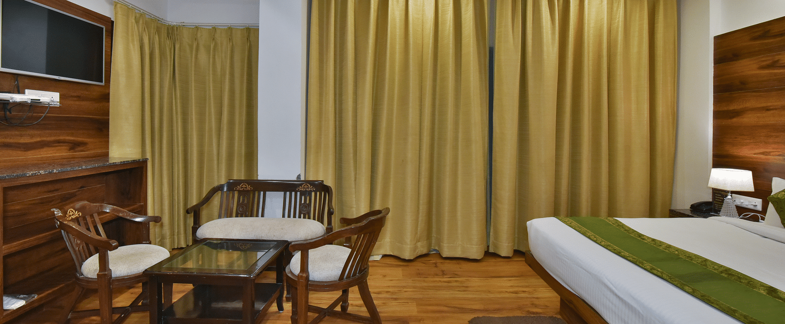 A large bed placed in front of two sofas at the Luxury Room Without Balcony at DLS Highland Resort and Spa, Mussoorie.